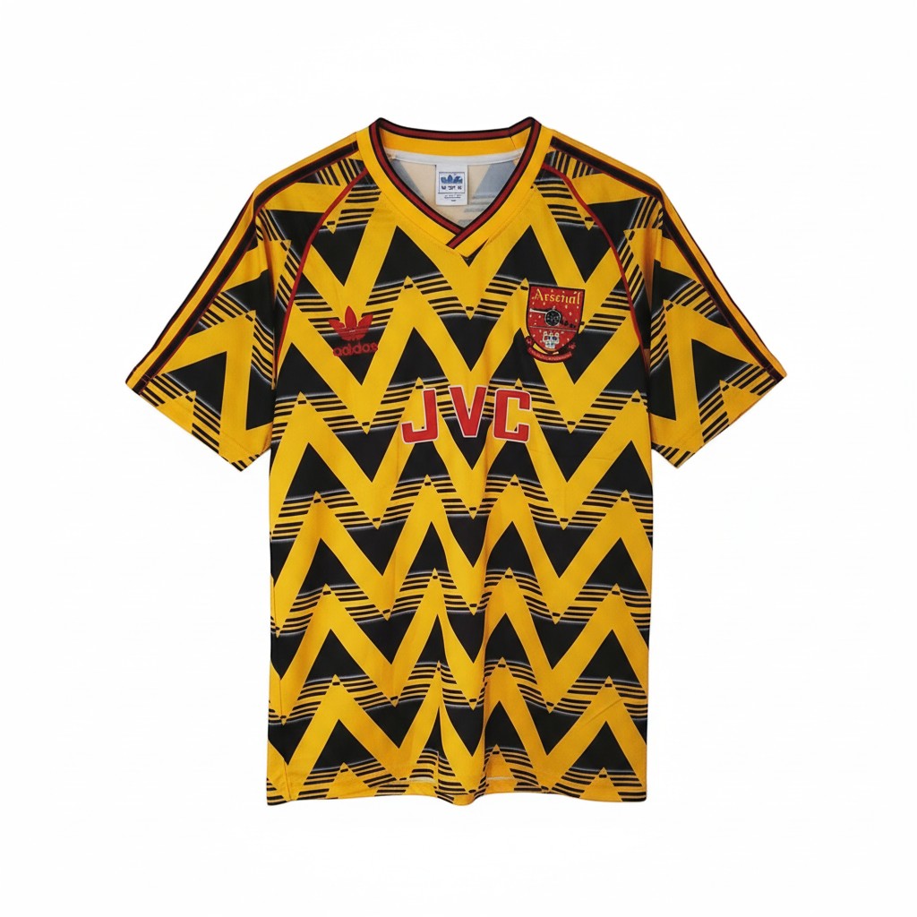 Hinchas Sportswear Store Arsenal 1991-93 retro 'Bruised Banana' away jersey. Yellow, black, and red zigzag pattern, Adidas logo, JVC sponsor.