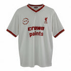 Hinchas Sportswear Store white Liverpool FC 1985/86 retro away shirt with red V-collar, sleeve cuffs, and 'Crown Paints' sponsor. Features LFC crest and commemorative patch.