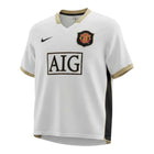 Hinchas Sportswear Store Manchester United 2006/07 retro white jersey with gold V-collar and cuffs, black side panels, Nike logo, and AIG sponsor.