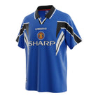 Hinchas Sportswear Store Manchester United 1996-97 retro third jersey in royal blue, black, and white. Features Umbro branding, Sharp sponsor, and chevron details.